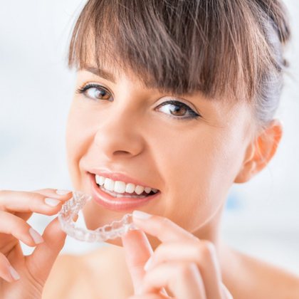 A woman holding a clear aligner