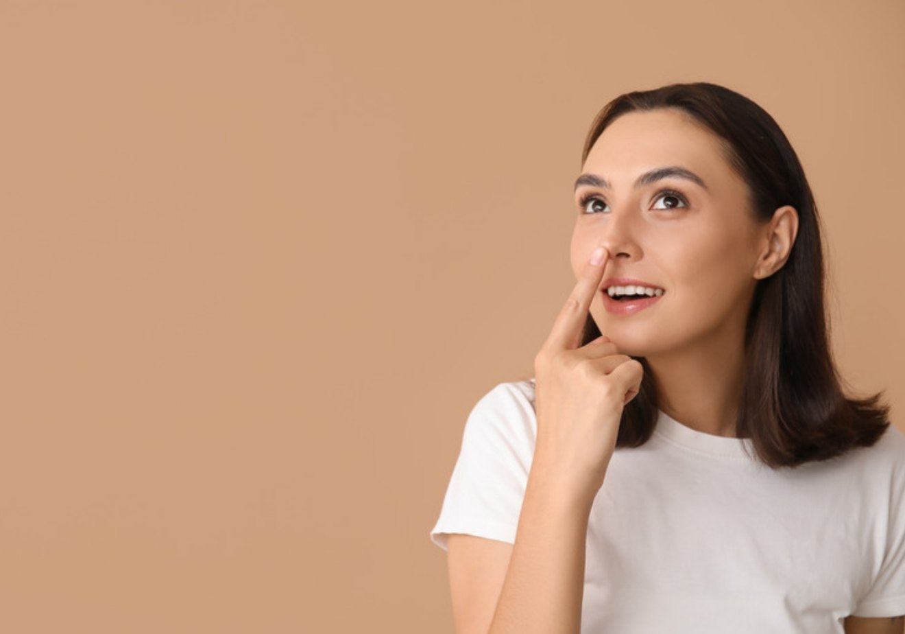 A smiling woman touching her nose